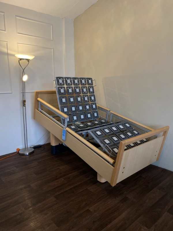 Ötfunkciós prémium betegágy állítható pozícióban, oldalkorláttal és modern ágyráccsal.